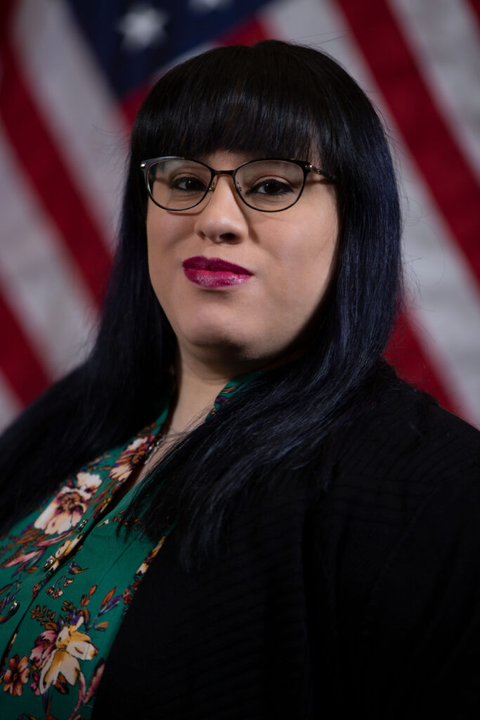 Person with glasses, dark hair, American flag