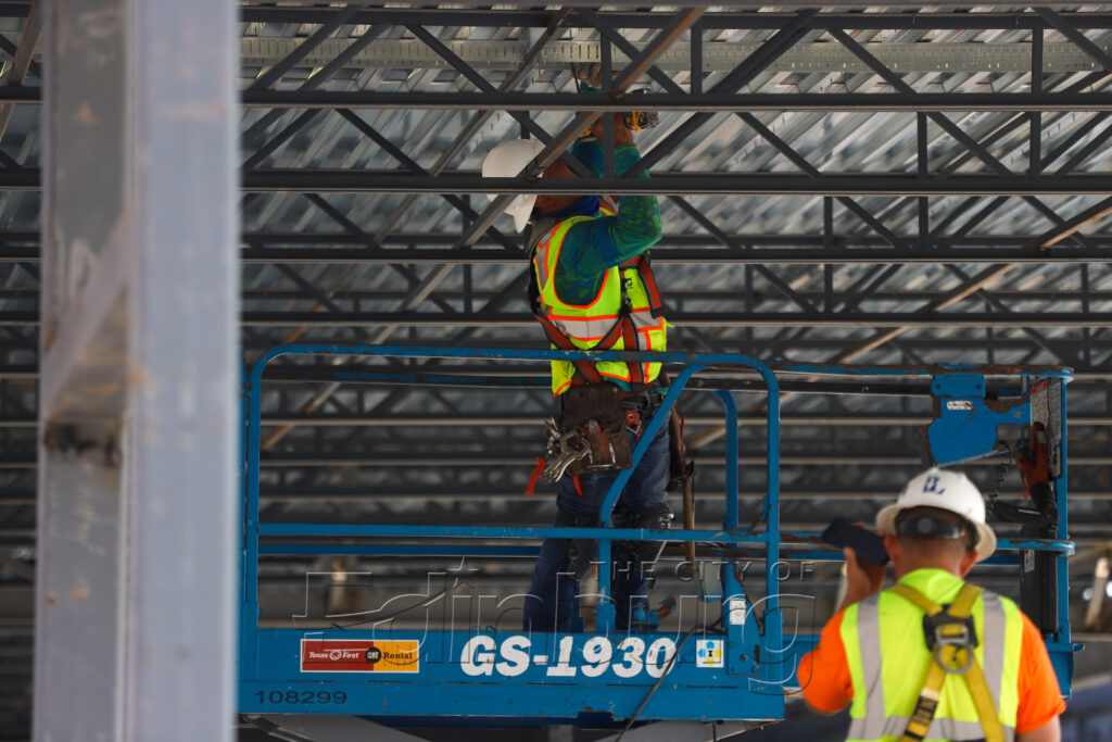 Construction worker on scissor lift under metal roof