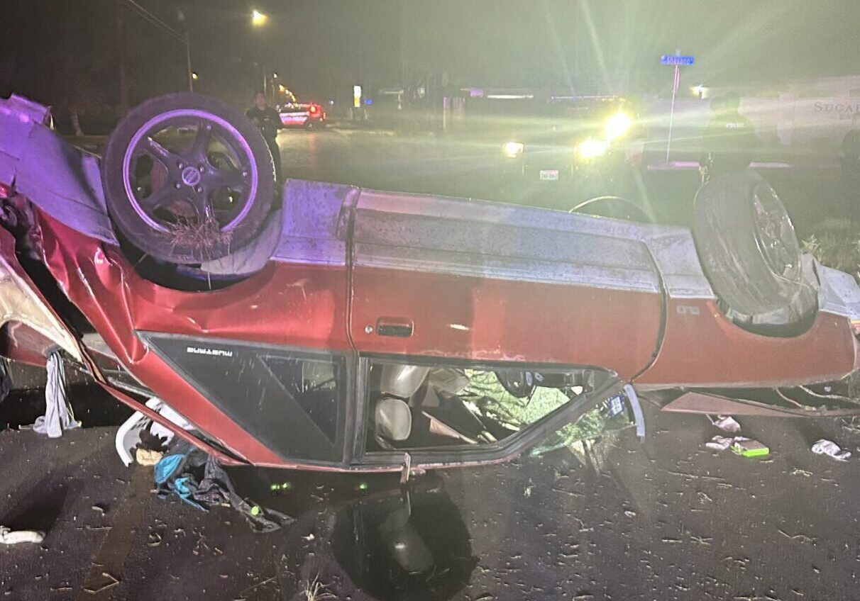 Overturned red car at nighttime crash scene