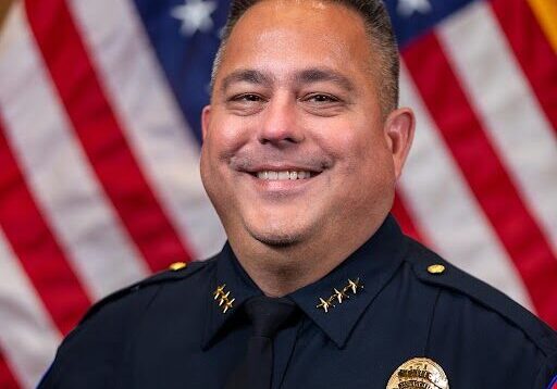 Smiling police chief in front of American flags