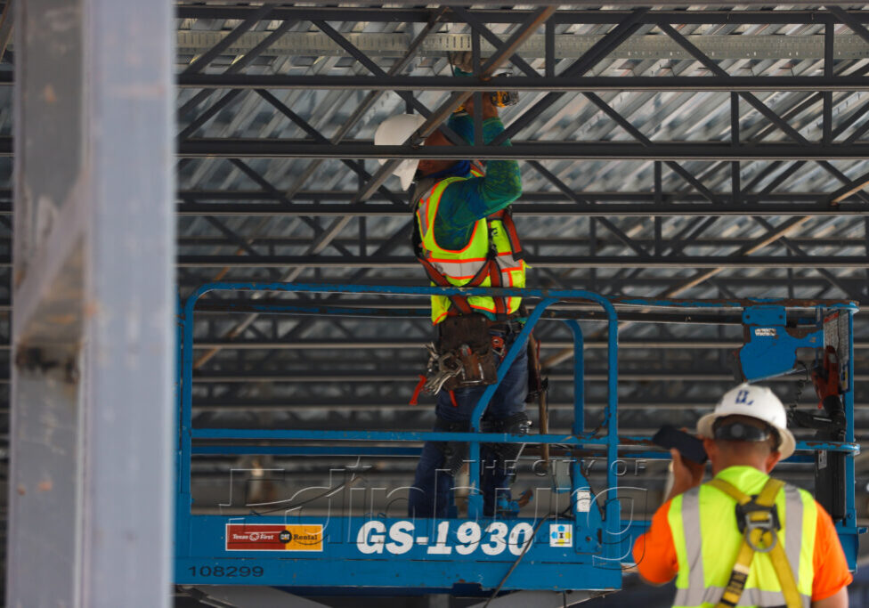 Construction worker on scissor lift under metal roof