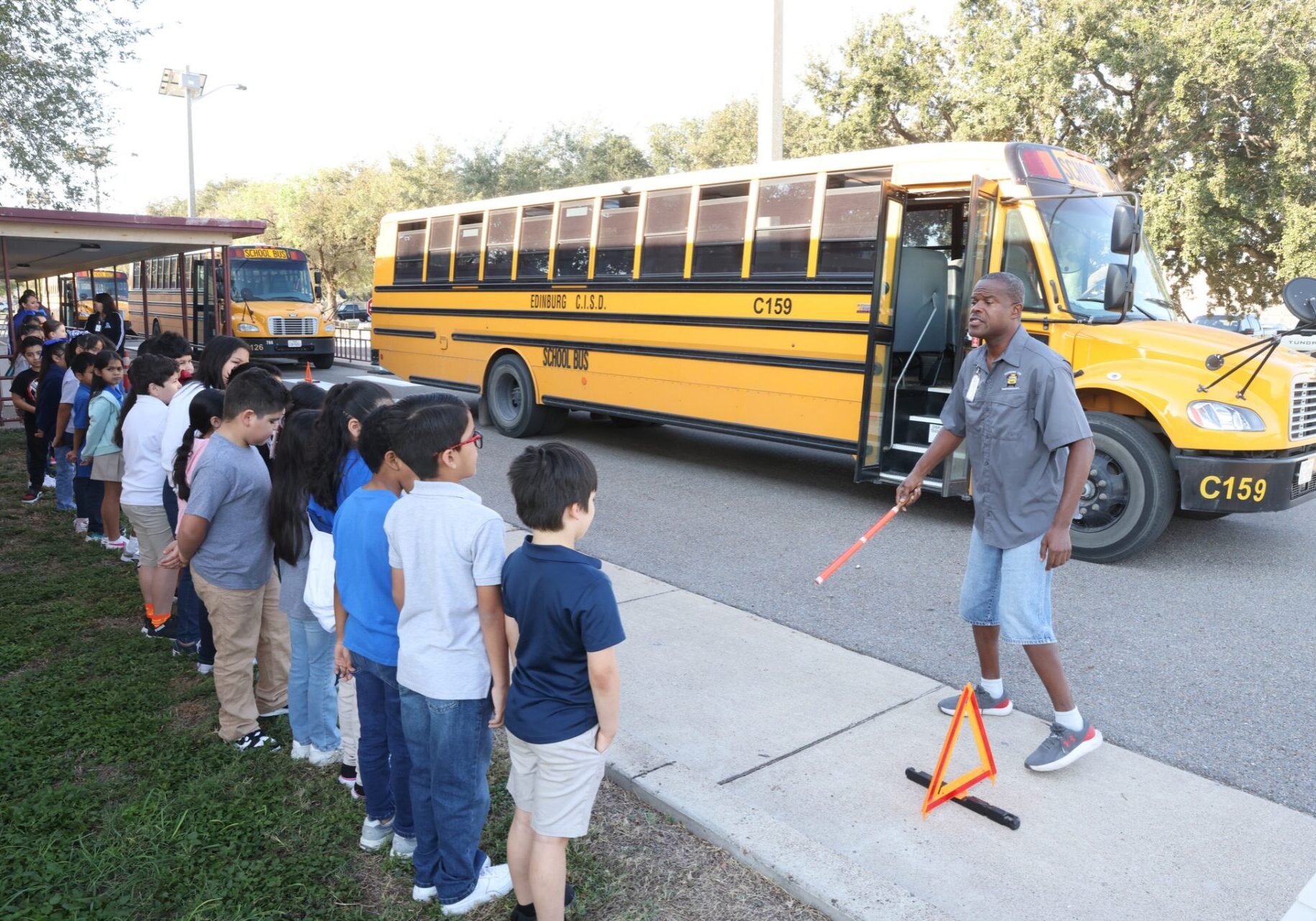 Schoolchildren lined up beside yellow school bus