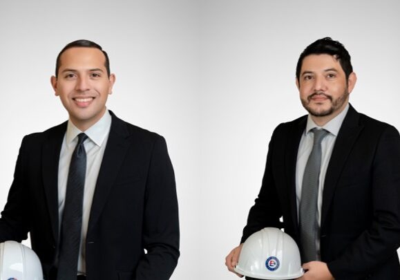 Two men in suits holding white hard hats