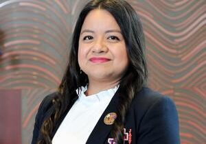 Smiling professional woman in blazer, patterned background