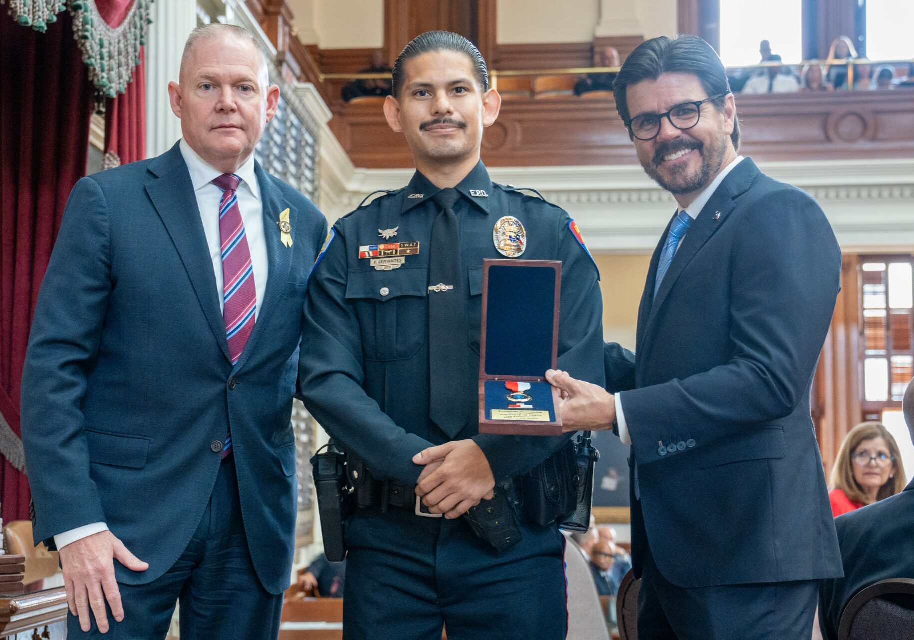 Police officer receiving award between two officials