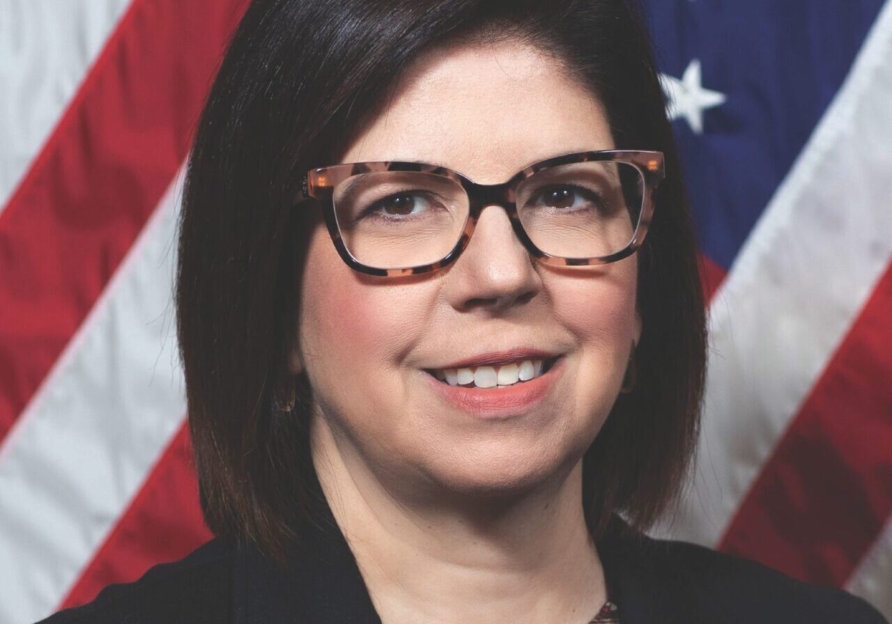 Woman wearing glasses smiling before American flag