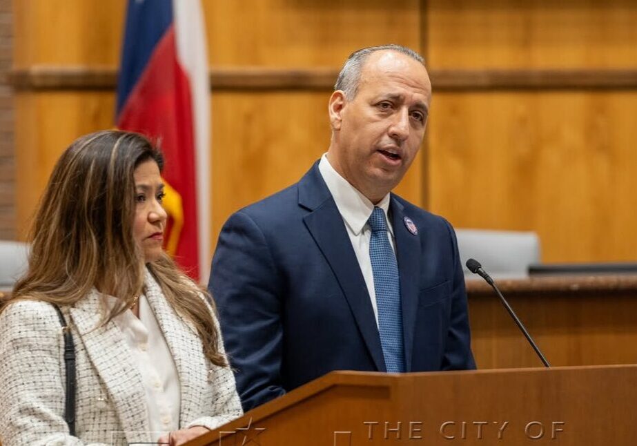 Man speaking at podium with woman beside him