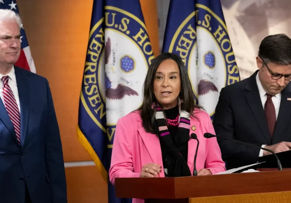 Three officials at podium with U.S. House flags