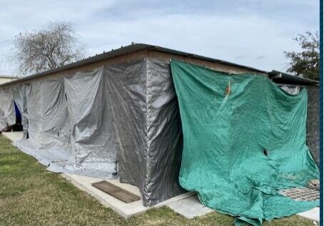 House exterior covered with gray and green tarps