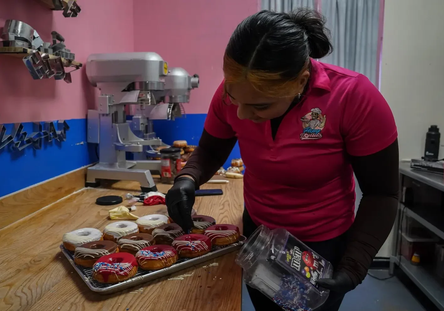Baker decorating colorful donuts on tray