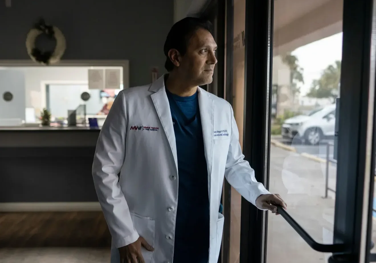 Doctor in white coat looking out window