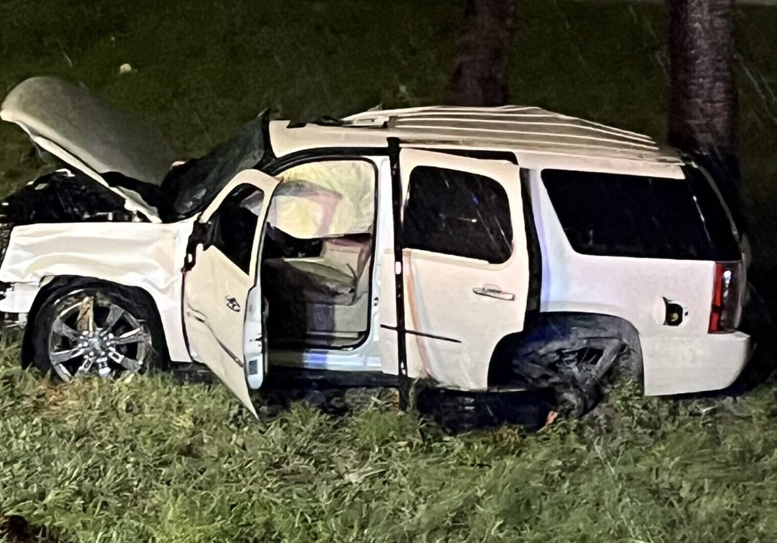 Wrecked white SUV with open doors