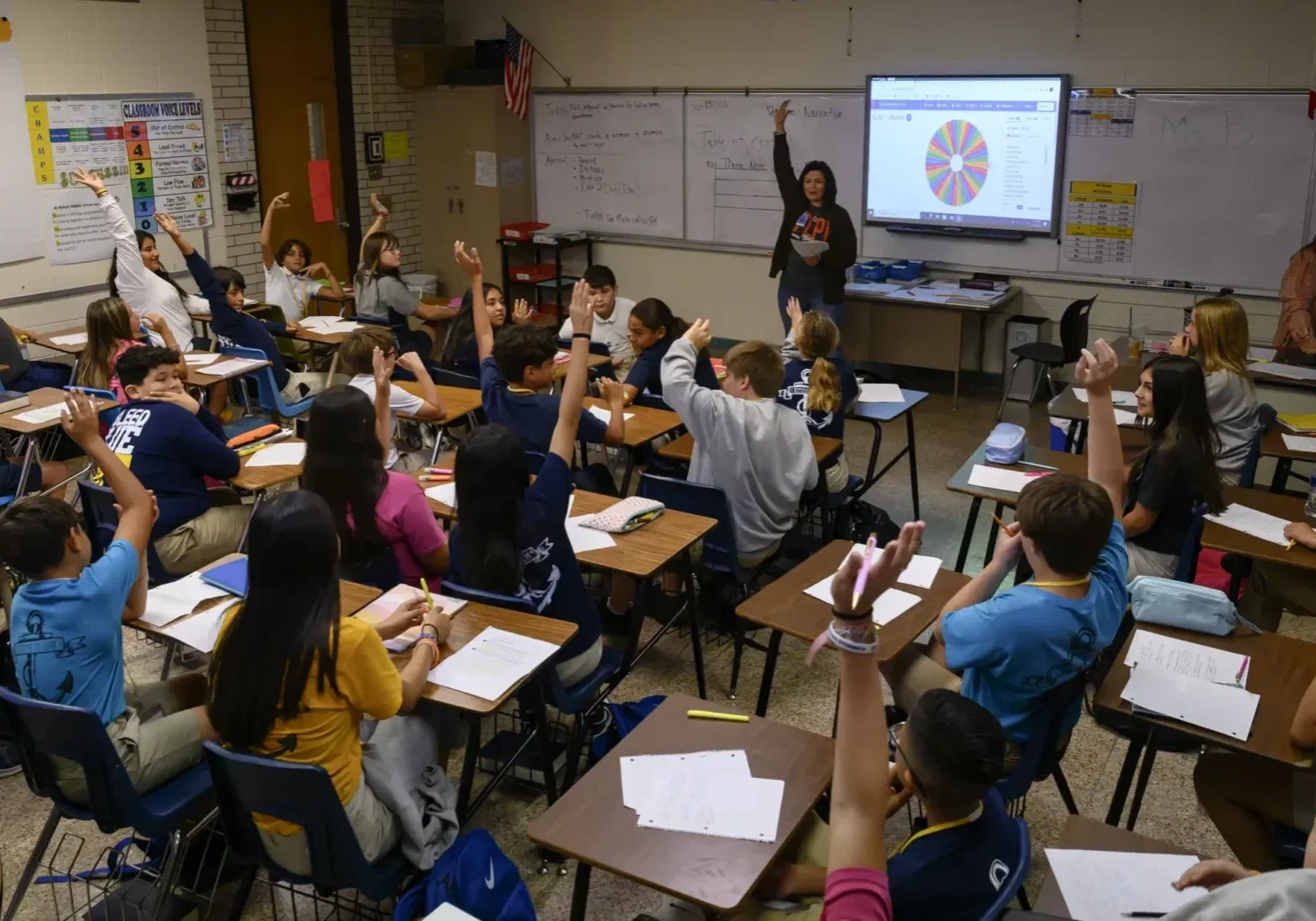Teacher and students raising hands in classroom
