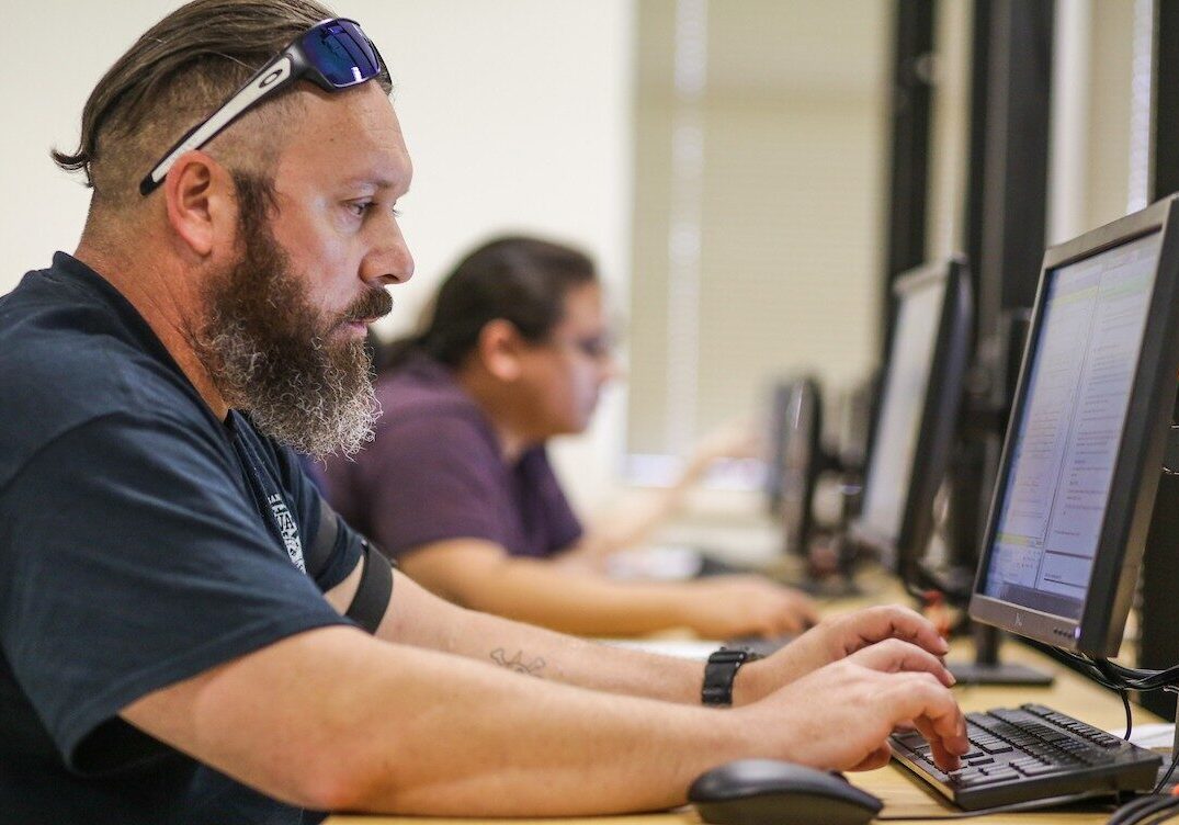 Bearded man typing at desktop computer in classroom