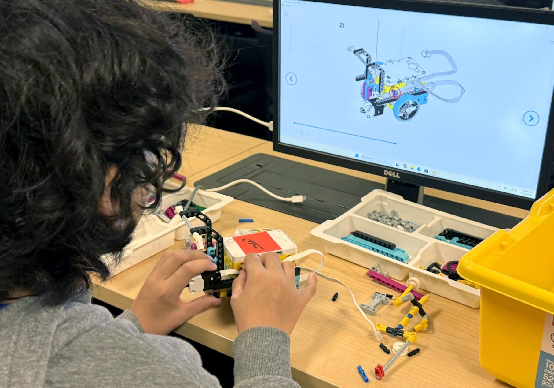 Student assembling robotics kit following computer instructions