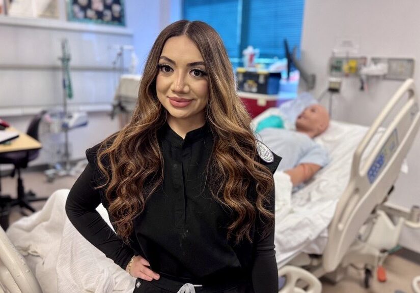 Smiling woman in medical uniform by hospital bed