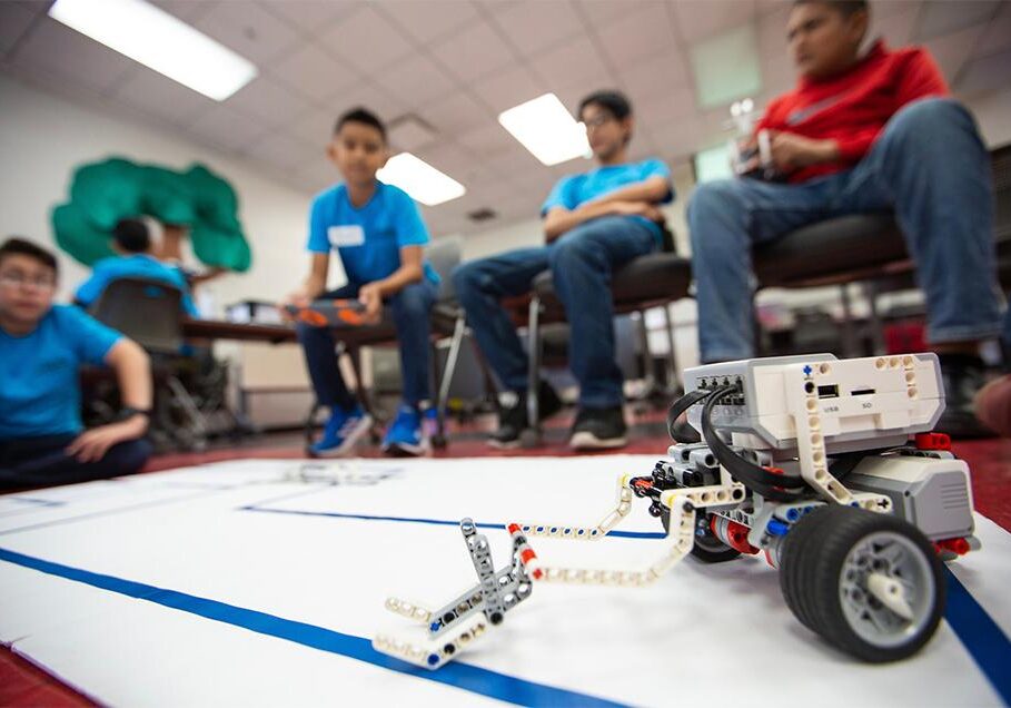 Students observing LEGO robot on competition mat