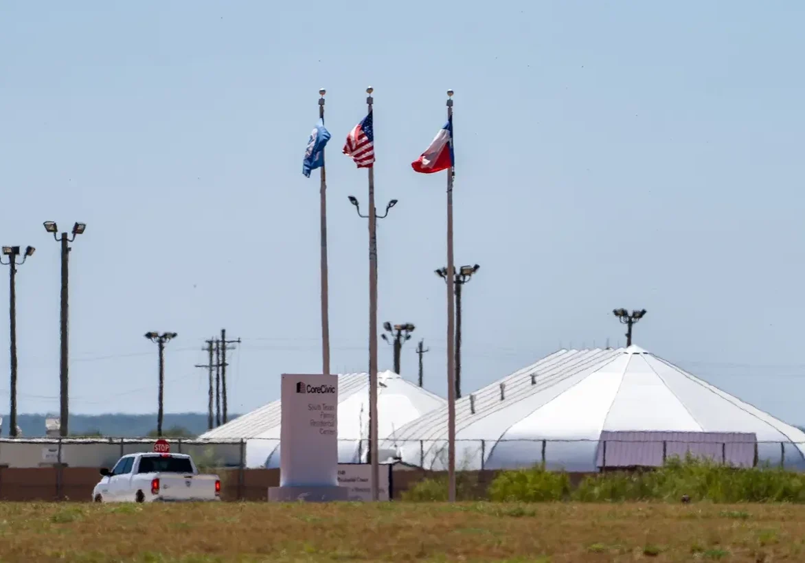 Three flags above white dome tent facility