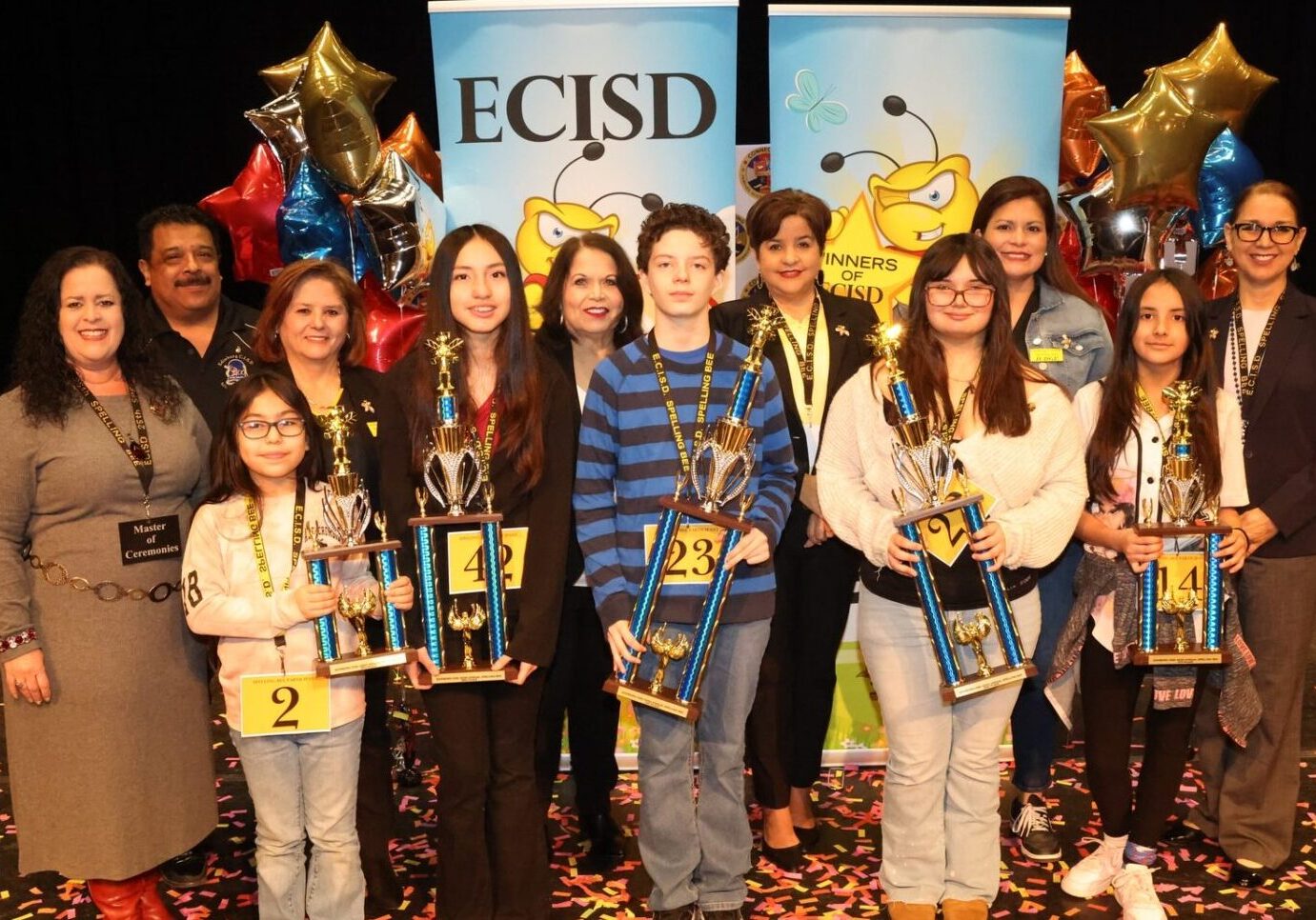 Students and adults with trophies onstage