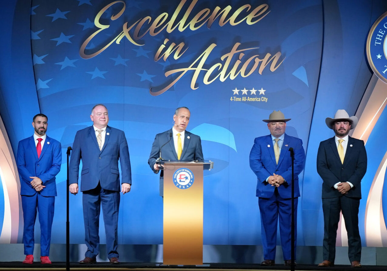 Five men in suits standing on stage