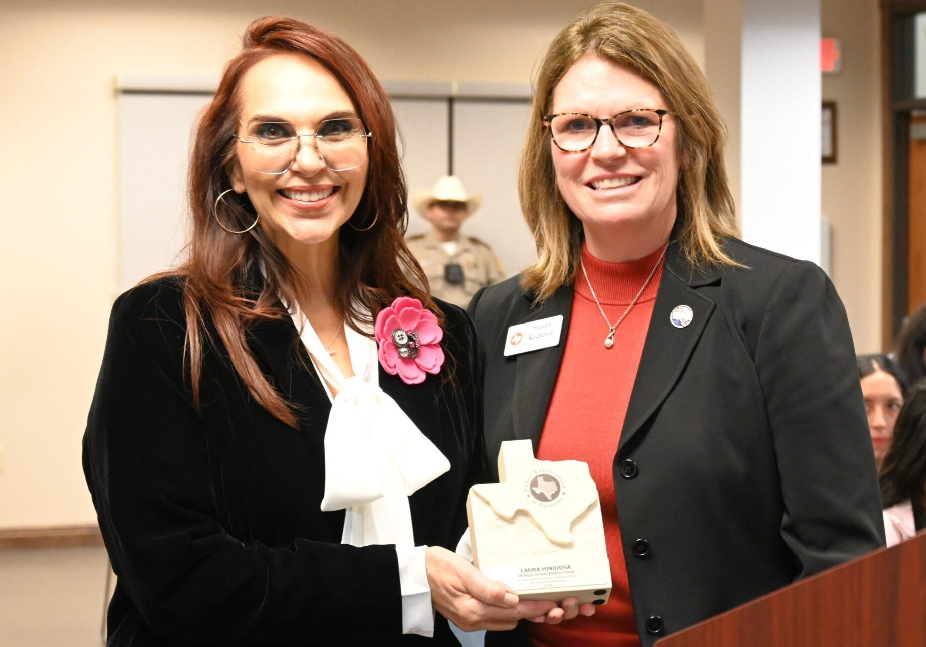 Two smiling women holding award plaque