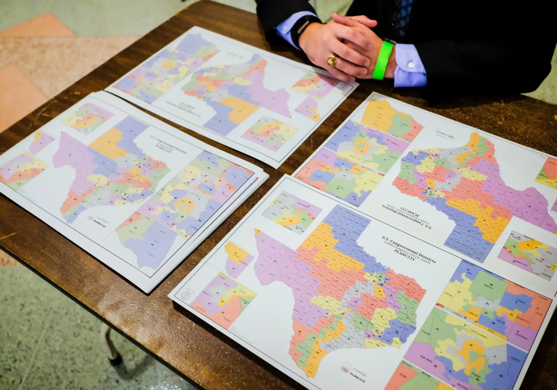 Four colorful Texas district maps on table