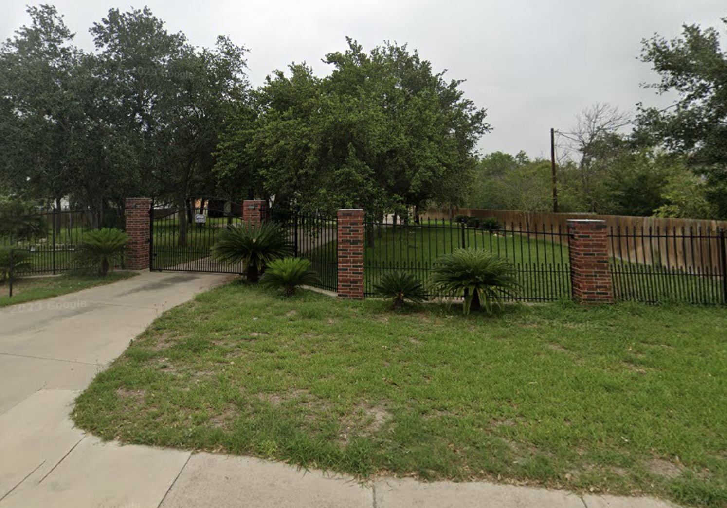 Driveway and iron gate with brick pillars