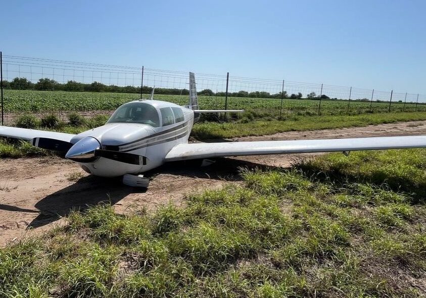 Small single-engine airplane parked on dirt field